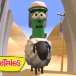 Green VeggieTales character wearing a head covering rides a fluffy gray sheep toward the camera in a desert canyon, VeggieTales logo in corner.
