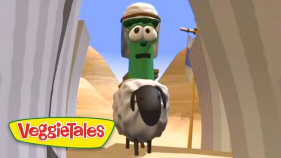 Green VeggieTales character wearing a head covering rides a fluffy gray sheep toward the camera in a desert canyon, VeggieTales logo in corner.