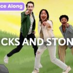 Three youths point at the viewer as a bold 'STICKS AND STONES' title appears; top-left shows a purple 'Dance Along' badge with a monkey logo on a bright background.